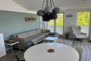 Ein modernes Wohnzimmer mit einem Ecksofa, einem runden Esstisch und minimalistischem Design.