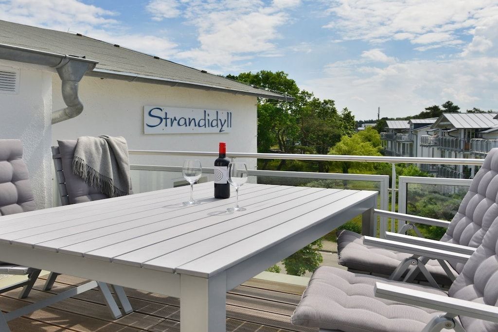 Eine Terrasse im Freien mit Tisch, Stühlen, einer Weinflasche und Gläsern.
