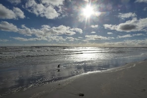 Ein Strand mit Wellen, blauem Himmel und strahlender Sonne.