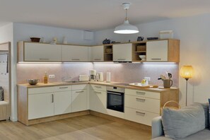 Eine moderne Küche mit weißen Schränken, einem eingebauten Backofen und einer Arbeitsplatte mit verschiedenen Küchenutensilien.