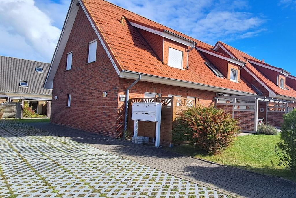 A two-story brick building with a sloped roof, a covered porch, and a paved driveway.
