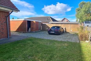 Ein Wohnhaus mit einem Auto auf der Einfahrt, Ziegelbau und Holzzaun.