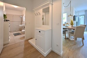 Een moderne badkamer met douche, toilet en wastafel. Boven de wastafel hangt een spiegel en eronder bevindt zich een klein kastje.