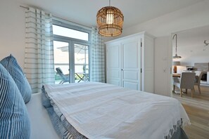 Een slaapkamer met een groot bed, een raam met gordijnen, een hanglamp en uitzicht op het landschap.
