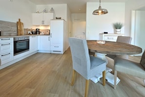Eine moderne Küche mit weißen Schränken, einem Holztisch und einer Pendelleuchte.
