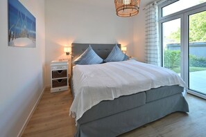 Ein Schlafzimmer mit einem Bett, Nachttischen, einer Lampe und einem Fenster.