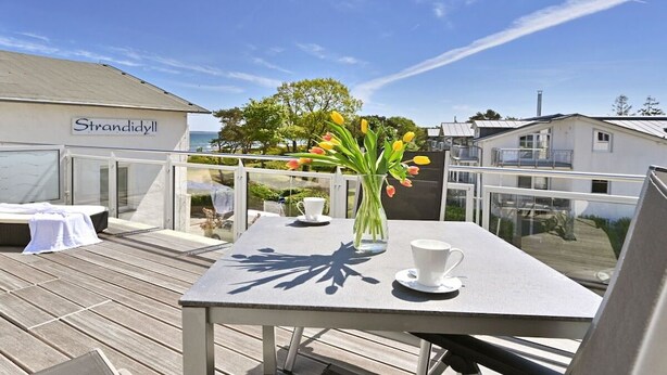 Ein Balkon mit Tisch, Stühlen und einem Blumenstrauß.