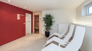 Ein Zimmer mit roter Wand, einem Blumentopf und weißen Stühlen.