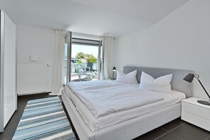 Et moderne hotelværelse med en stor seng, et sengebord, en lampe og udsigt ud.