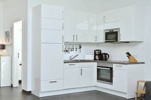 A modern kitchen with white cabinetry, a built-in oven, and a coffee maker. - Holiday apartment in Juliusruh with Wi-Fi (Juliusruh)