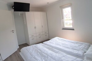 Quarto com cama, guarda-roupa e janela.