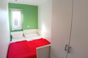 A small room with a bed, a window, and a wardrobe. - Jette beach bungalow (Glowe)