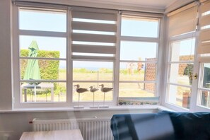 Quarto com janela saliente, radiador, sofá azul e vista para o exterior.