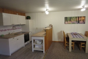 A compact kitchen with white cabinets, a wooden countertop, and a dining area with a table and chairs. - Holiday home in Granzow with swimming pool (Granzow)