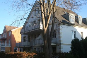 Un edificio residenziale a più piani con balconi e un albero di fronte.