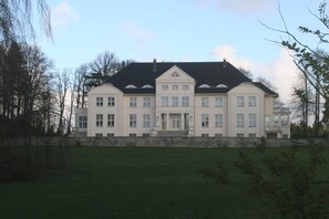 Ein großes, symmetrisches Gebäude mit einem zentralen Eingang, zahlreichen Fenstern und einem gepflegten Rasen davor.