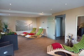 Ein moderner Lounge-Bereich mit Rattanmöbeln, einer Glastür zu einem Zimmer und einem großen abstrakten Gemälde an der Wand.
