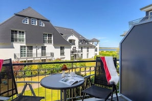 Ein Balkon mit Tisch, Stühlen und Blick auf ein großes Haus.