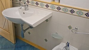 Ein Badezimmer mit einem weißen Waschbecken, einem Bidet und einem Spiegel über dem Waschbecken.