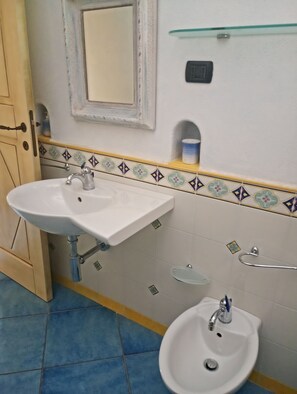 Een badkamer met een wit wastafel, een bidet en een spiegel boven de wastafel.