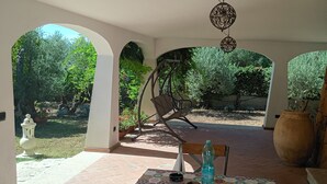 Ein Zimmer mit einem gemusterten Tisch, einer Pendelleuchte und Blick auf einen Garten durch einen Bogen.