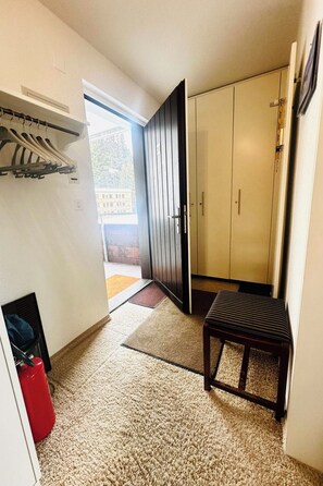 Ein Flur mit Kleiderständer, Sitzbank, Schrank und einer Tür zum Ausgang.