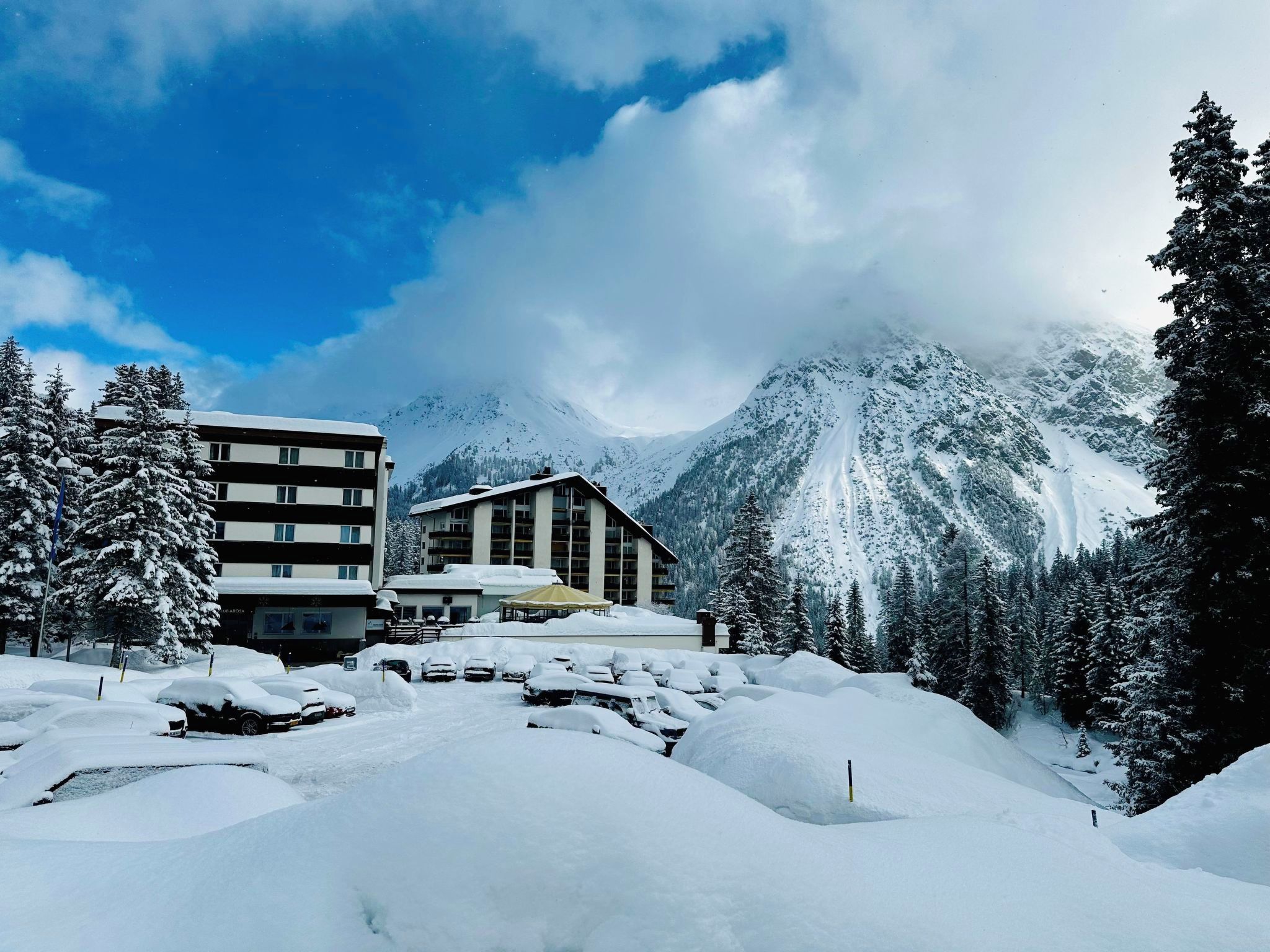 A snow-covered mountain landscape with a building featuring multiple windows and a covered outdoor area.