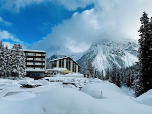 Eine verschneite Berglandschaft mit einem Gebäude mit mehreren Fenstern und einem überdachten Außenbereich.