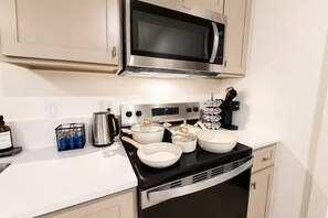 A kitchen with a microwave, stove, and various pots and pans. - King Bed-Unbeatable Location-Bishop Arts- Unit 4 (Dallas)