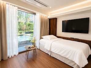 A hotel room with a bed, a TV, a small table with a cup, and a view of a pool and greenery outside. - Wangsimni Stay Forest (Seoul)
