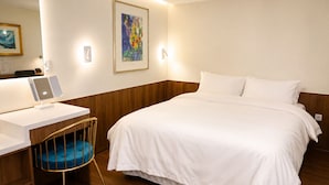 Hotellihuone, jossa on sänky, työpöytä tietokoneella ja tuoli.