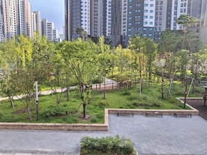 Un área de parque ajardinada con árboles, bancos y un sendero pavimentado.