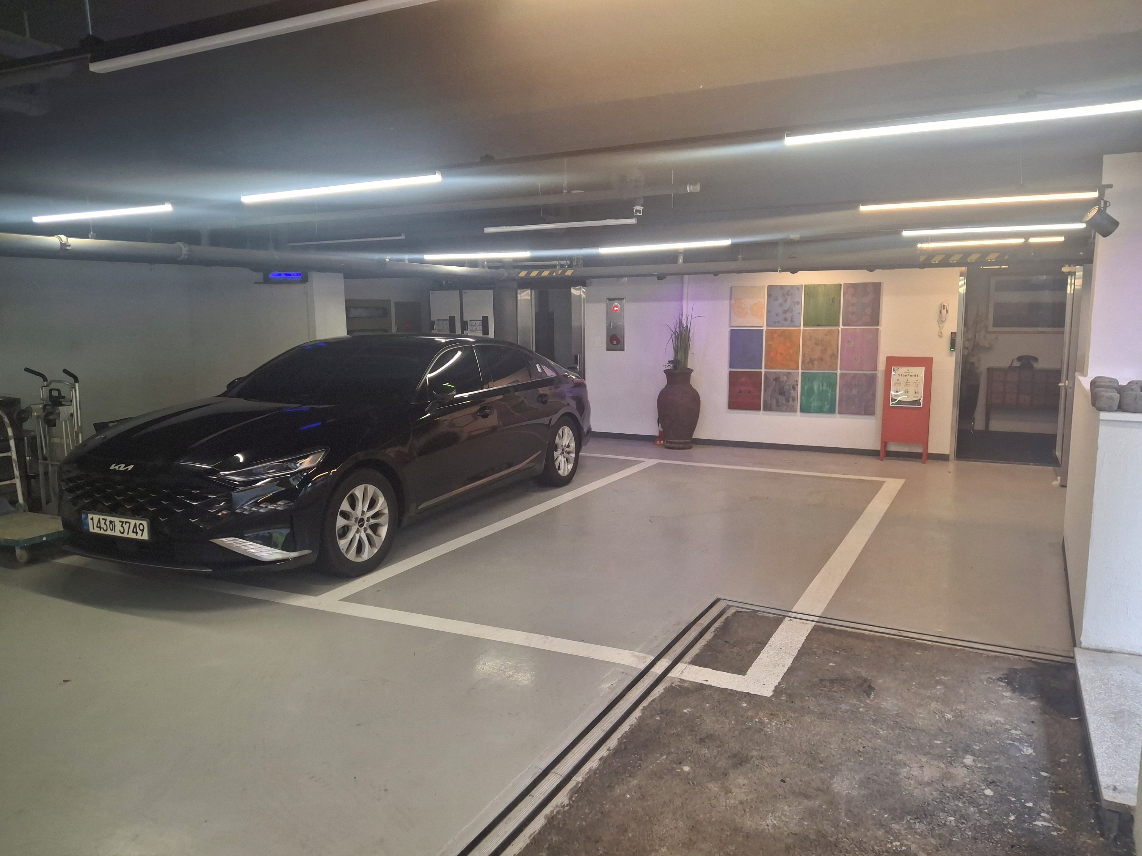 A parking garage with a black car parked in a designated space.