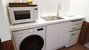 Une cuisine compacte équipée d’un four à micro-ondes, d’un évier, d’un lave-vaisselle et d’une machine à laver.