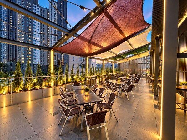 An outdoor dining area with tables and chairs, surrounded by a railing and potted plants. - Stay Forest  (Seoul)
