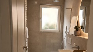 Een moderne badkamer met een douche, toilet en wasmachine.