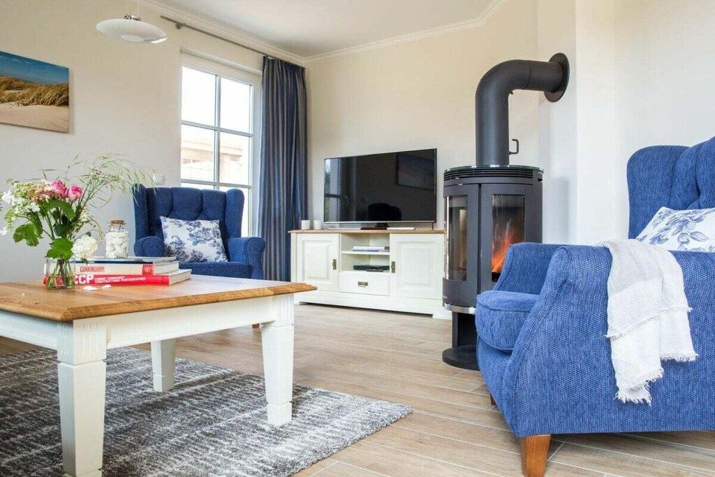 A living room with a blue sofa, a wooden coffee table, a TV, and a wood-burning stove.