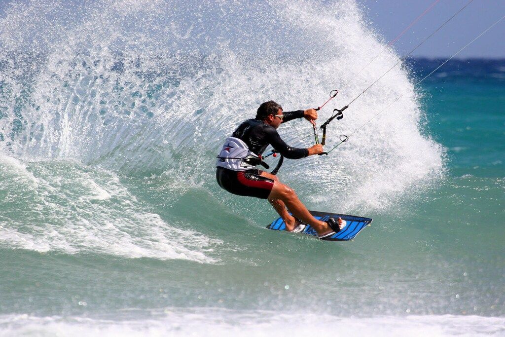 Una persona practicando windsurf sobre una ola.