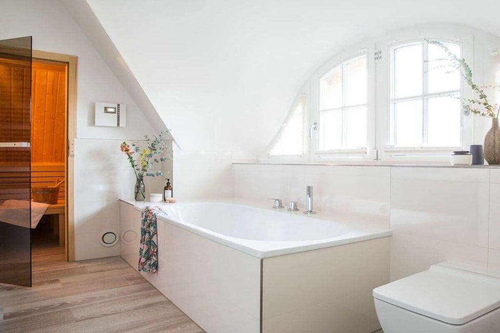 Ein modernes Badezimmer mit einer freistehenden Badewanne, einer Toilette und einem Fenster mit Tageslicht.