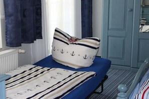 A bedroom with a bed, a window with curtains, a radiator, and a door. - Holiday apartment with 1 bedroom (Sassnitz)