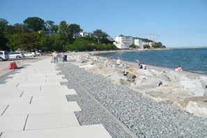 A coastal promenade with a rocky shoreline, a clear sky, and buildings in the background. - Holiday apartment with 1 bedroom (Sassnitz)