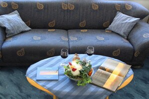 Quarto com sofá e mesa posta com um livro, copos e um objeto decorativo.