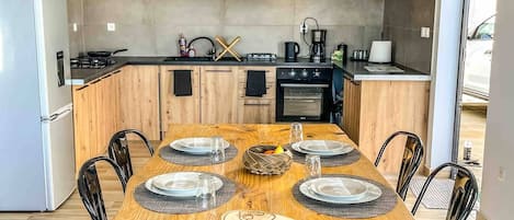 Cocina moderna con una isla central, armarios de madera y una mesa de comedor para cuatro.