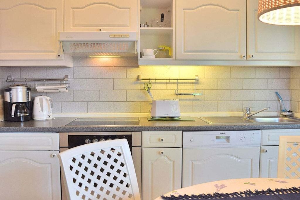 A kitchen with white cabinets, a dishwasher, a coffee maker, and a kettle.