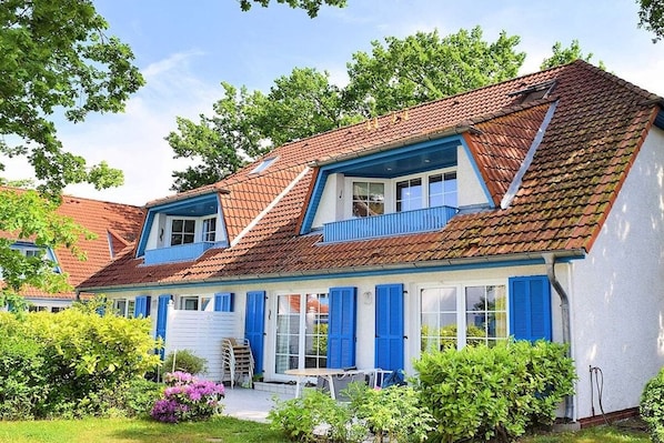 A two-story house with a sloped roof, blue shutters, and a white garage door. - Knut in the Mill Park (Prerow)