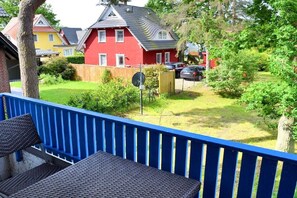 A residential property with a blue balcony, a red house, and a well-maintained garden. - Knut in the Mill Park (Prerow)