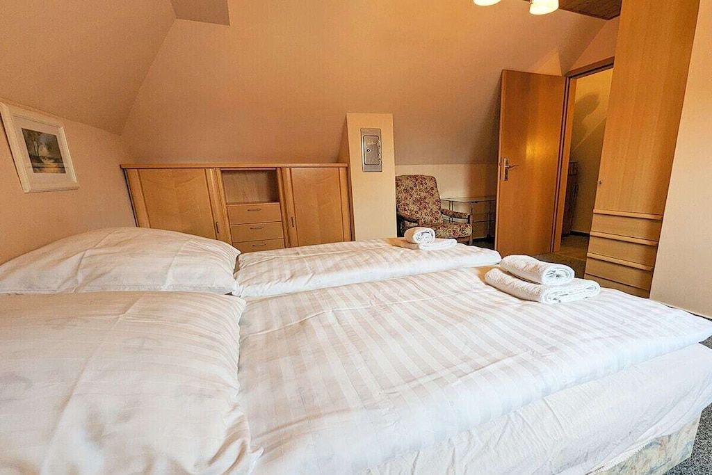 Une chambre d’hôtel avec deux lits, une armoire en bois, une chaise et une petite table.