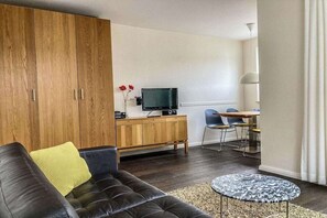 A modern living room with a leather sofa, a wooden cabinet, a television, and a dining area with chairs. - in the house "Holiday Idyll" (Seebad Ahlbeck)