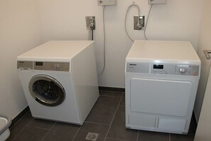 A laundry room with two white washing machines, a wall-mounted electrical outlet, and a vented cabinet. - Holiday apartment in Glowe with swimming pool (Glowe)