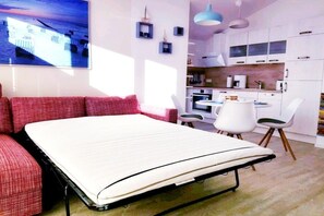 A compact room with a bed, a sofa, a dining table, and a kitchenette. - Holiday apartment in Glowe with swimming pool (Glowe)